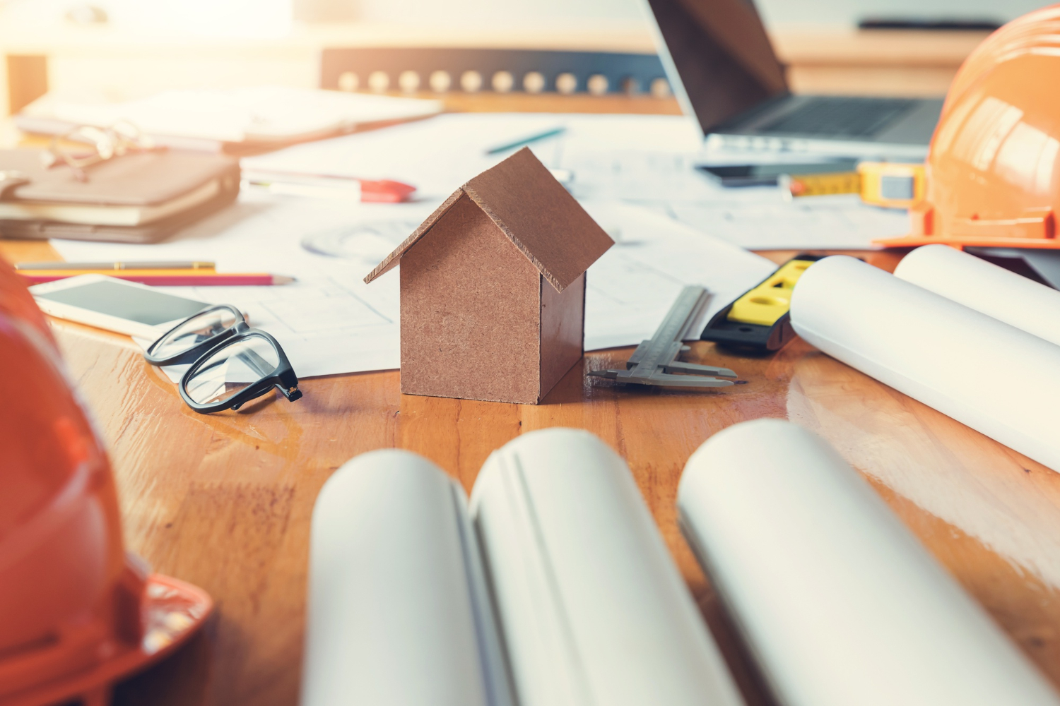 Modèle de maison et plans sur le bureau de l'architecte en heures de travail.